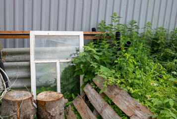 An old wooden window frame was thrown into a garbage heap in the backyard of a suburban area