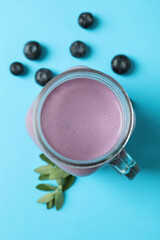 Fresh blueberry smoothie and ingredients on blue background
