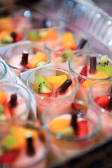 Close up of assorted fruit desserts in tray on table with bokeh background. Catering service. No people. Selective focus. 