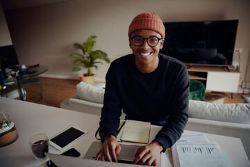 African American male working from home and browsing on his laptop. African American man writing notes and typing on his laptop. High quality photo