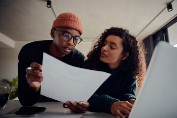 Close up of mixed race couple using laptop for online banking. Happy African American couple working together at home. High quality photo