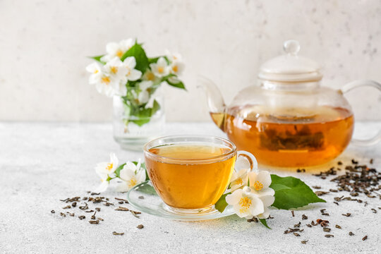 Composition with cup of jasmine tea and flowers on light background
