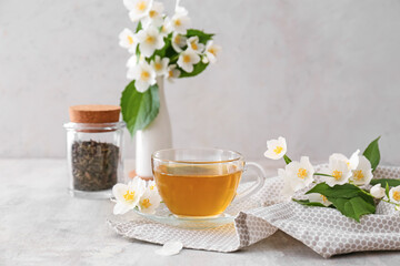 Composition with cup of jasmine tea and flowers on grunge background
