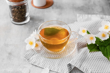 Cup of jasmine tea and flowers on grunge background