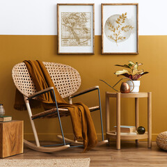 Stylish composition of living room interior with design rattan armchair, two mock up poster frames, plants, cube, palid and personal accessories in honey yellow home decor. Template.