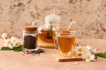 Composition with glass of jasmine tea, dry leaves and flowers on color background