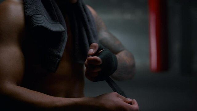 Man pulling bandages on hands. Guy wrapping hands with punching wraps