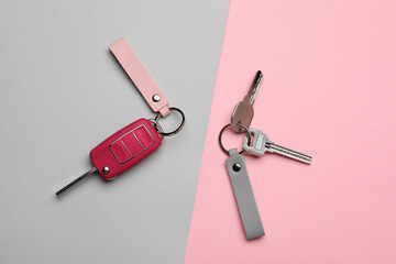 Keys with leather keychains on color background