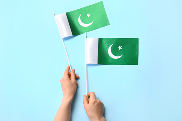 Female hands with Pakistan flags on color background