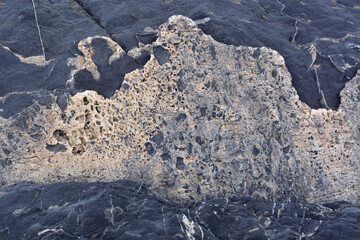 Light pattern as foam and texture on a dark stone, close-up