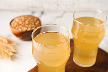 Glasses of fresh kvass on light background