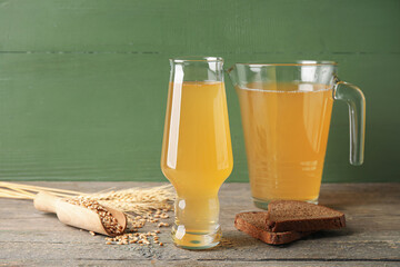 Glass and jug of fresh kvass on color wooden background