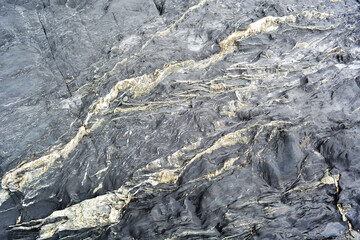 Black stone texture with diagonal stripes, close-up, natural abstraction
