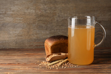 Jug of fresh kvass on wooden background