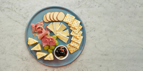 Set of crackers, ham, cheese and olives on a plate