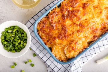Baking dish with tasty potato casserole on light background