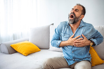  Mature man having strange chest pain. People, healthcare and problem concept - close up of man suffering from heart ache. Man holding his chest in discomfort with his hands due to pain in that area