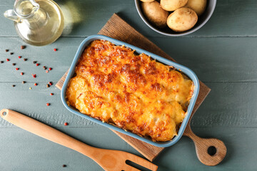 Baking dish with tasty potato casserole on color wooden background