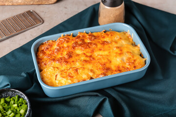 Baking dish with tasty potato casserole on light background