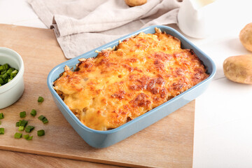 Baking dish with tasty potato casserole on light background