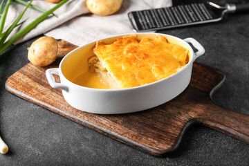 Baking dish with tasty potato casserole on dark background