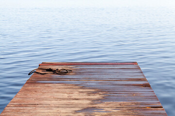Obraz premium Wet rope lays at the end of small wooden pier