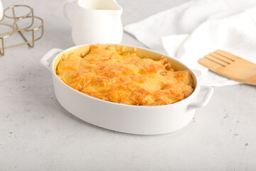 Baking dish with tasty potato casserole on light background