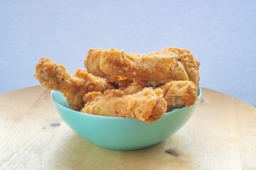A plate with fried chicken legs on a wooden table.