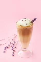 Glass of tasty lavender latte and flowers on color background