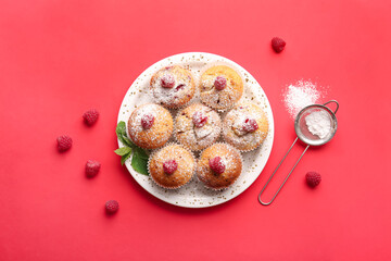 Plate with tasty raspberry muffins and sieve on color background
