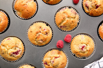 Baking tin with tasty raspberry muffins, closeup