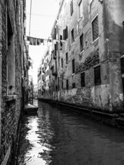 Picturesque little canal street in Venice with a boat and clothes drying in the sun