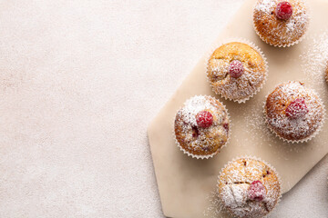 Fototapeta na wymiar Board with tasty raspberry muffins on light background