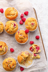 Board with tasty raspberry muffins on light background
