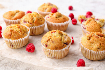 Parchment with tasty raspberry muffins on light background, closeup