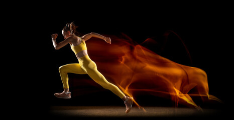 Flyer. Young woman, professional female athlete training isolated over black studio background in...