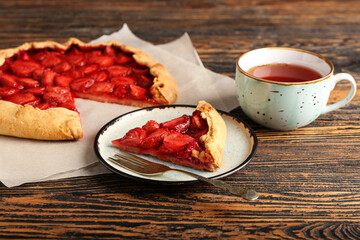 Plate with piece of tasty strawberry pie on wooden background