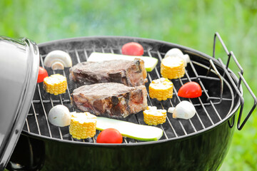 Barbecue grill with tasty steaks and vegetables outdoors, closeup
