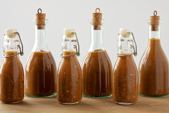 Bottles of chili hot sauce made from fermented chilies. Homemade Sriracha spicy sauce in bottles.