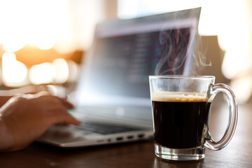Blurred of cup of hot coffee with businessman use computer