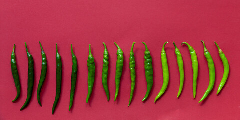 Different shades of green chilies on red background. Green de cayenne different heirlooms chili in...
