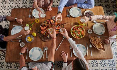 Crop friends with beer gathering at table with delicious food