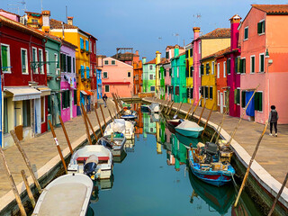 Fototapeta na wymiar Boats docking and colorful houses in a canal street houses on Burano island, Venice, One unrecognizable people on the background.