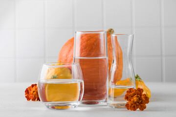 Autumn still life of pumpkins distorted through water in glasses. The concept of Thanksgiving or...