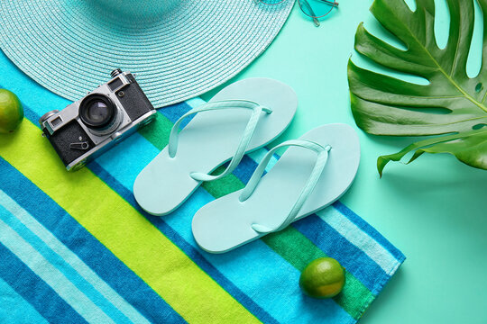 Set of beach accessories with photo camera and palm leaf on color background
