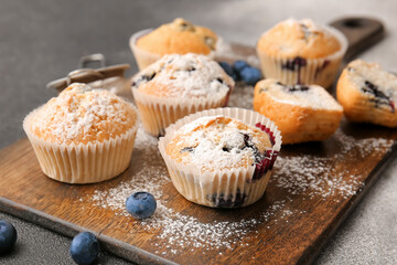 Board with tasty blueberry muffins on dark background