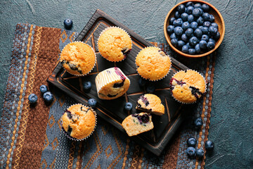 Composition with tasty blueberry muffins and berries on color background
