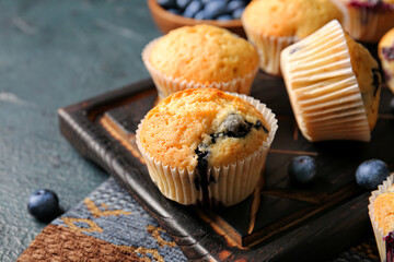 Tasty blueberry muffins on color background, closeup