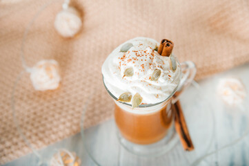 Pumpkin coffee in transparent cup and whipped cream with cinnamon. Autumn cappuccino or latte menu.