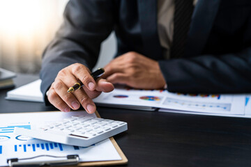 Fototapeta premium A male accountant or a business man uses a laptop to calculate investment results. And making financial reports on the desk Business finance accounting concept